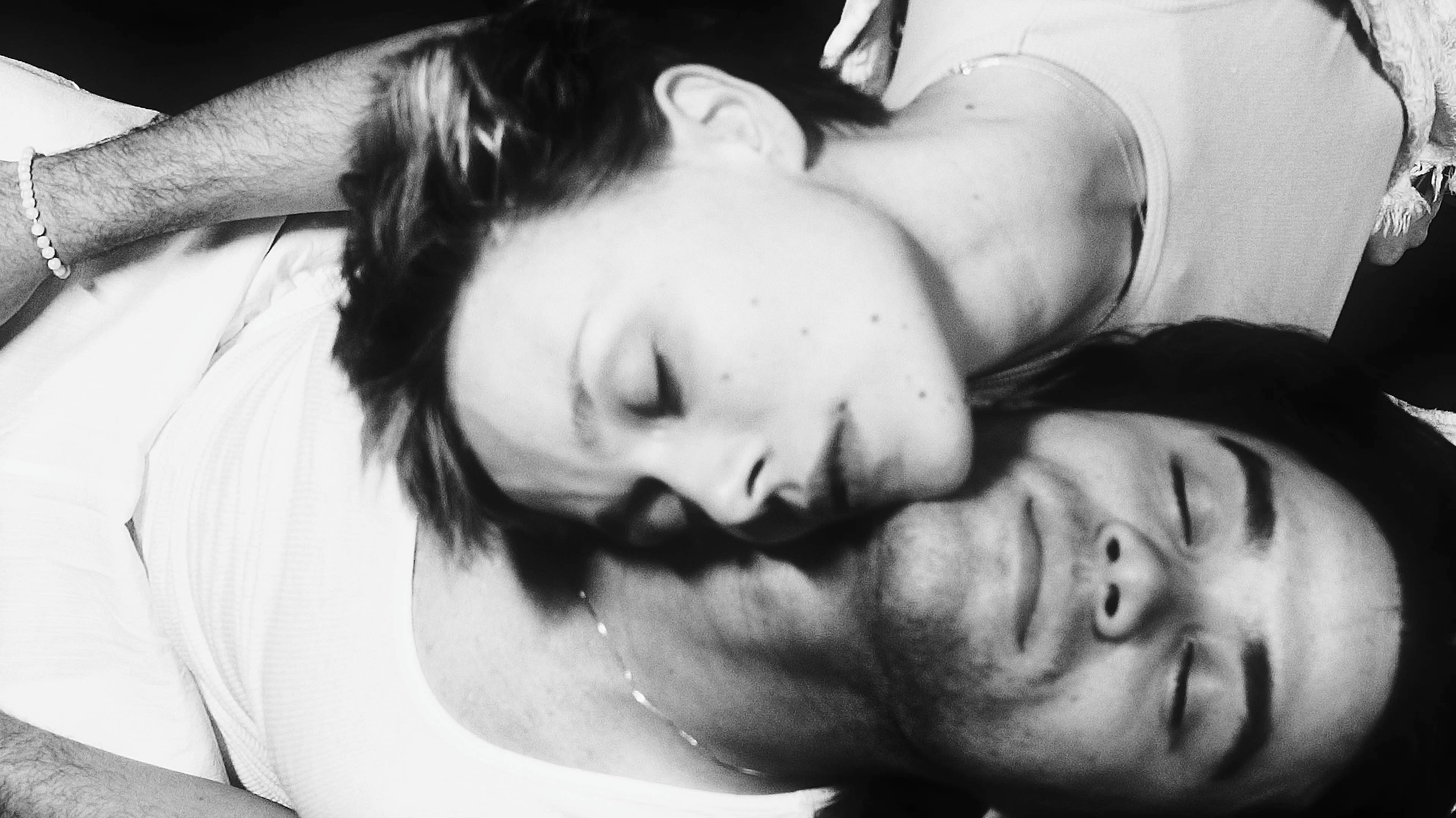 a black and white photo of a man and woman laying on top of each other